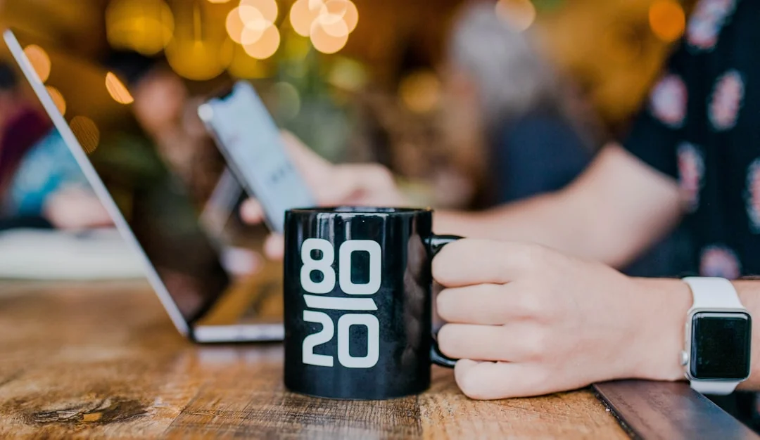 Des mains tenant un smartphone à côté d’un ordinateur portable avec des graphiques boursiers, illustrant le trading numérique.